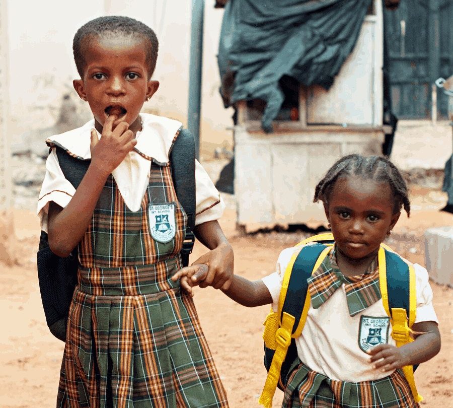 Two pupils in school uniform walking hand in hand.